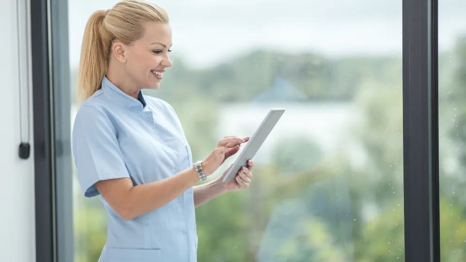 Profissional de saúde consultando um tablet em ambiente clínico claro