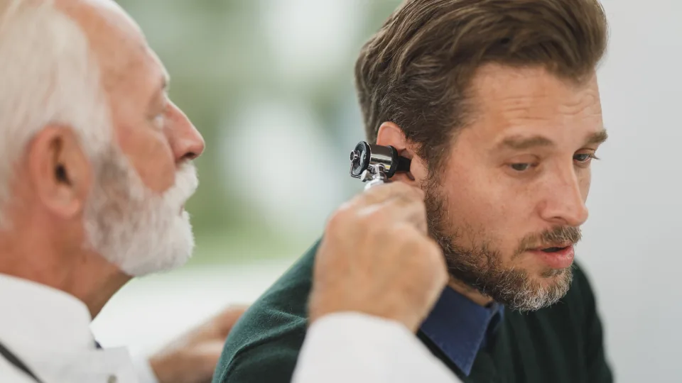 Médico examinando a orelha de um paciente em consultório